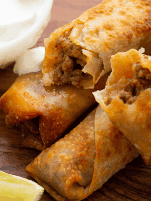 Golden, crispy homemade egg rolls filled with pork and vegetables, served with dipping sauce.