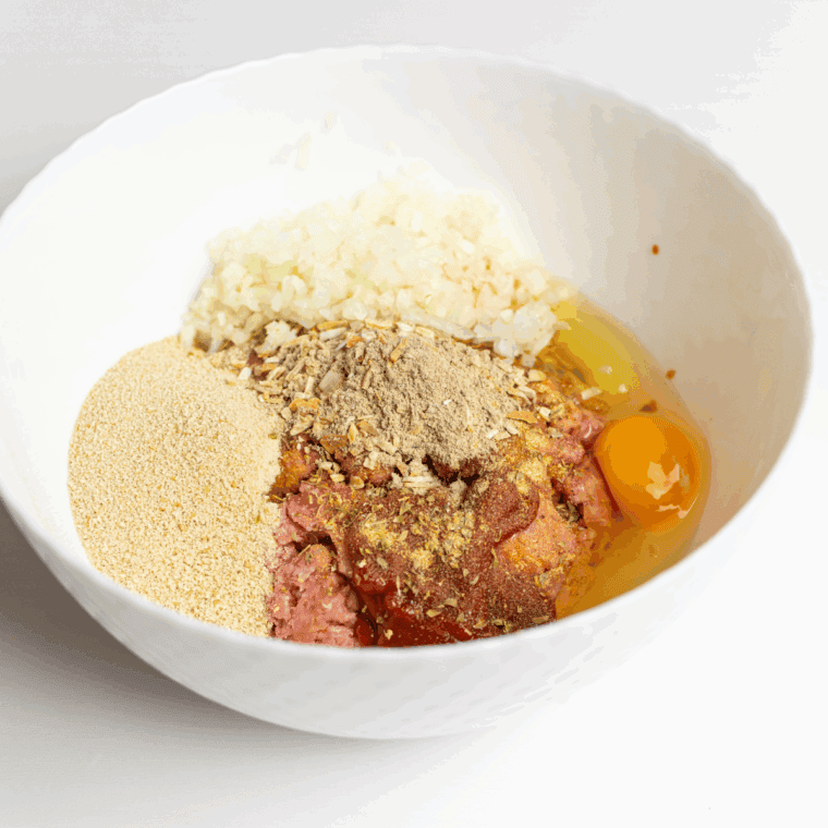 Mixing ground beef, chopped onion, Lipton Onion Soup Mix, breadcrumbs, eggs, ketchup, Worcestershire sauce, garlic powder, and black pepper in a large bowl until just combined.