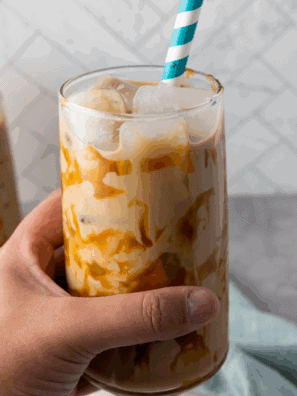 Glass of homemade McDonald’s-style caramel iced coffee with whipped cream and caramel drizzle on top.