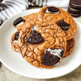 "Stack of fudgy Oreo brownie cookies topped with chunks of Oreo on a wire cooling rack"