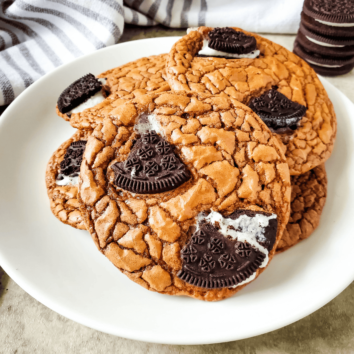 "Stack of fudgy Oreo brownie cookies topped with chunks of Oreo on a wire cooling rack"