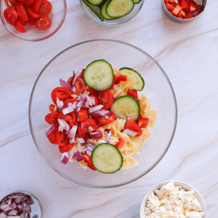 Adding all of the vegetables into the bowl with the pasta.