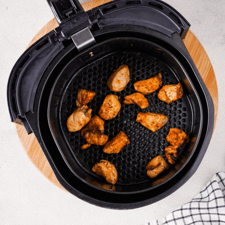 Marinated chicken thighs arranged in a single layer inside an air fryer basket.