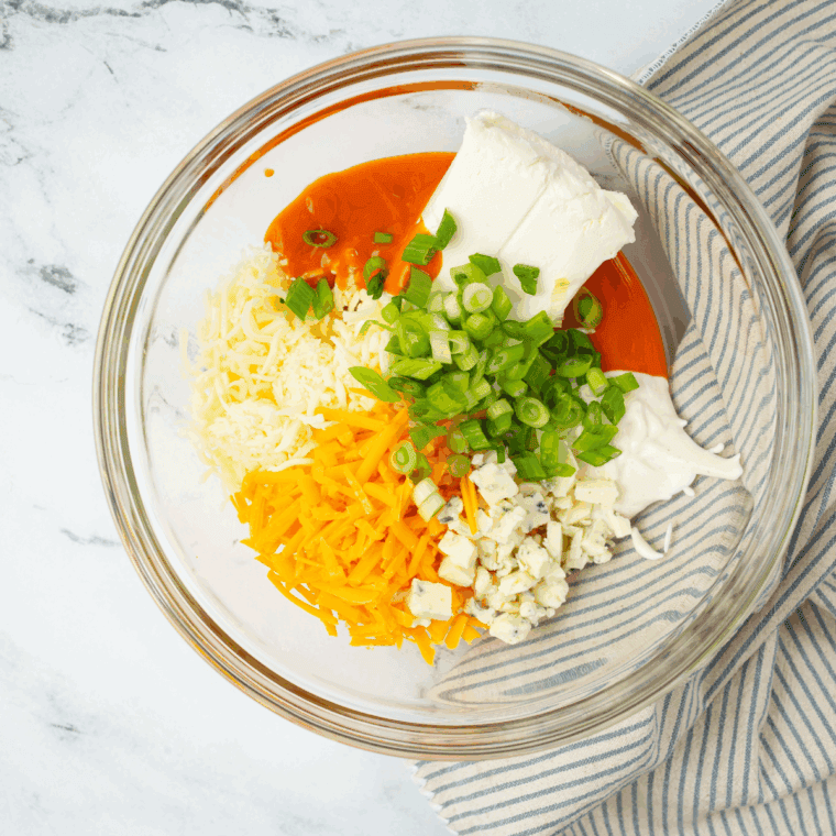 Mixing shredded chicken, cream cheese, ranch, and buffalo sauce in a large bowl until smooth.