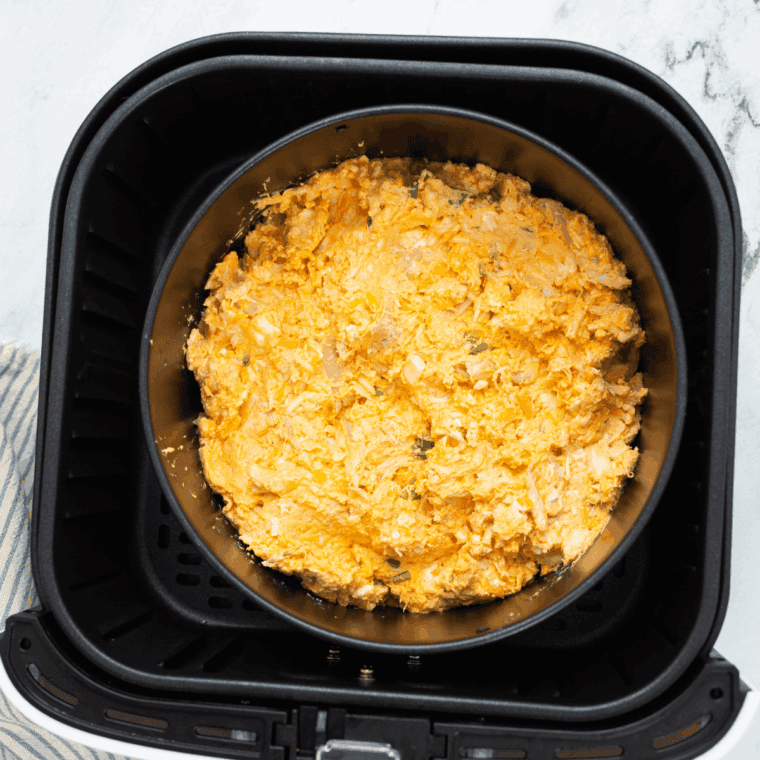 Buffalo chicken dip mixture spread evenly in a small air fryer-safe baking dish.