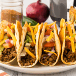 Crispy homemade Jack in the Box tacos filled with seasoned meat, melted cheese, lettuce, and taco sauce on a plate.