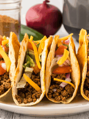 Crispy homemade Jack in the Box tacos filled with seasoned meat, melted cheese, lettuce, and taco sauce on a plate.