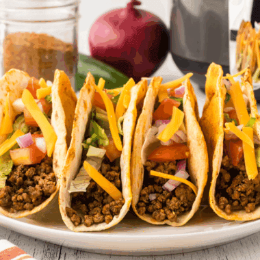Crispy homemade Jack in the Box tacos filled with seasoned meat, melted cheese, lettuce, and taco sauce on a plate.