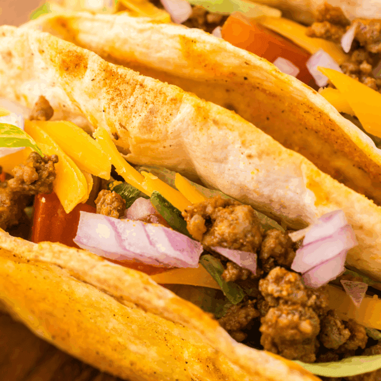 Golden crispy homemade Jack in the Box style tacos filled with seasoned beef, melted cheese, and fresh lettuce on a plate.