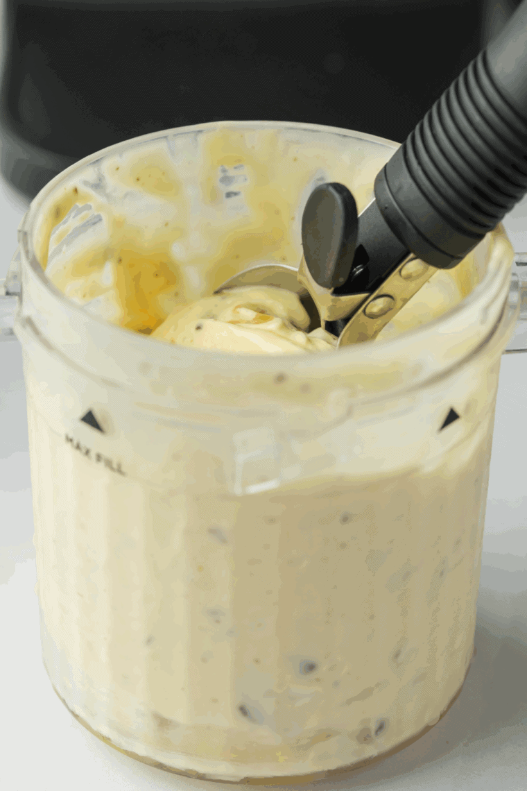 Scooping Americone Dream ice cream into a bowl with visible fudge and crunchy waffle cone pieces.