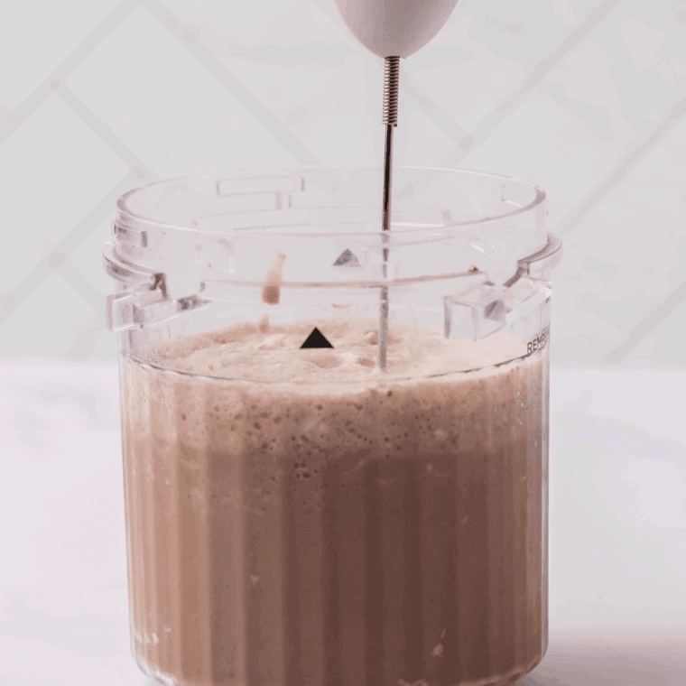 Pouring Starbucks Mocha Frappuccino drink into Ninja Creami container, adding coffee and chocolate syrup for blending.