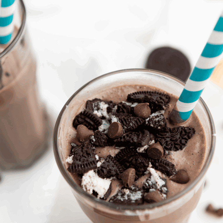 Homemade Ninja Creami Oreo shake topped with whipped cream and crushed Oreo cookies in a clear glass.