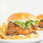 Crispy chicken sandwich with melted cheese, pickles, and hot honey drizzle on a toasted bun, Red Robin style.