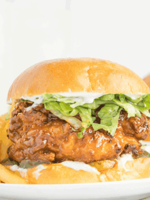 Crispy chicken sandwich with melted cheese, pickles, and hot honey drizzle on a toasted bun, Red Robin style.