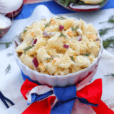 Red, White and Blue Potato Salad, featuring creamy potatoes, fresh cherry tomatoes, and blueberries, perfect for summer BBQs and patriotic celebrations.