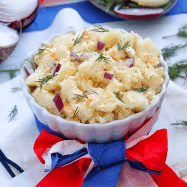 Red, White and Blue Potato Salad, featuring creamy potatoes, fresh cherry tomatoes, and blueberries, perfect for summer BBQs and patriotic celebrations.