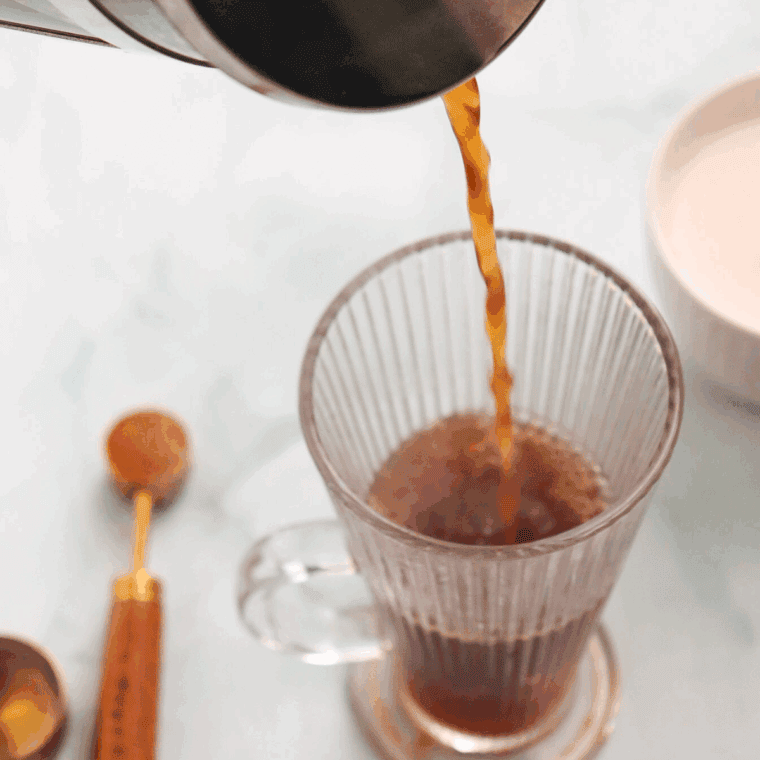 Pouring brewed coffee into a mug.
