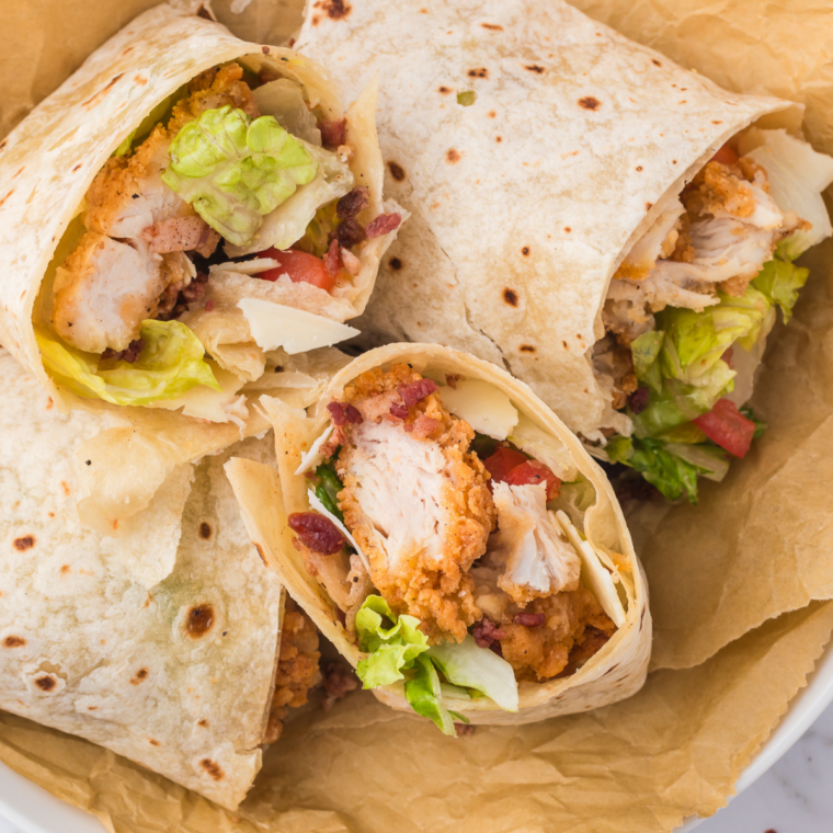 Air Fryer Chicken Caesar Wrap sliced in half with crispy chicken, romaine lettuce, Parmesan cheese, and Caesar dressing