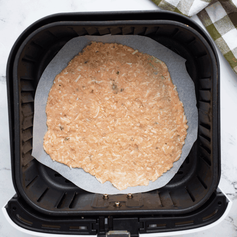 Placing chicken crust in air fryer basket ready for cooking.