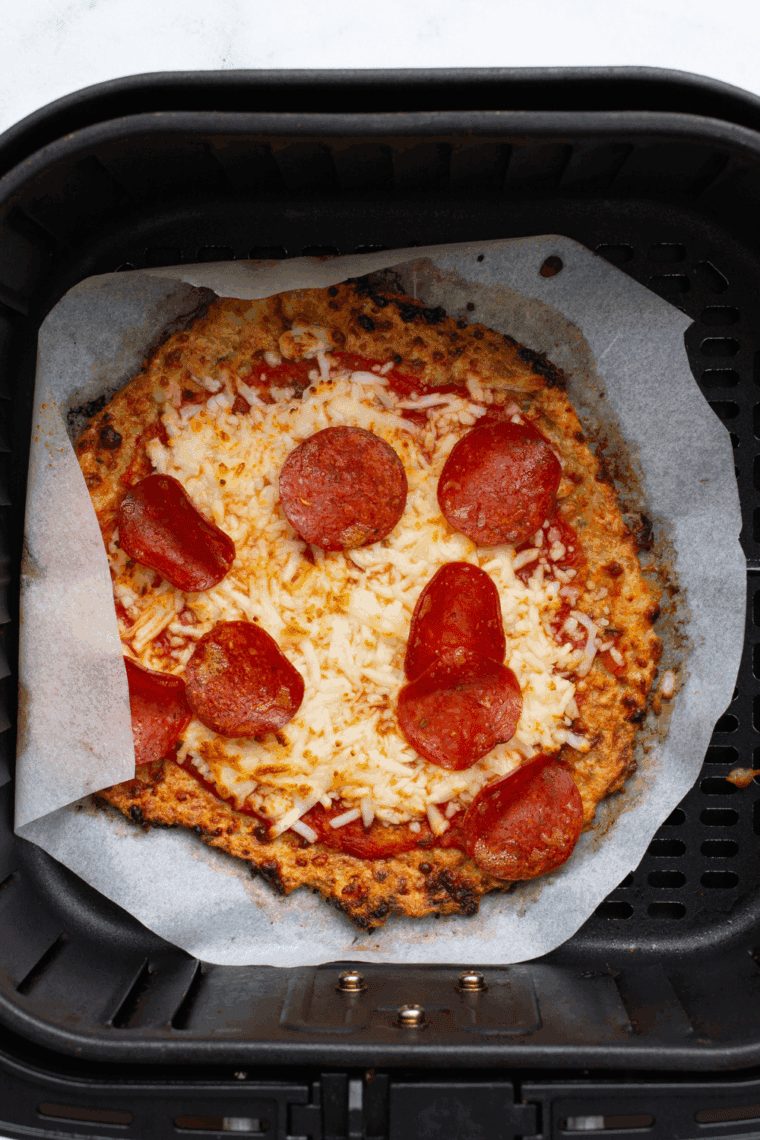 Air fryer chicken crust pizza topped with melted cheese, marinara sauce, and pepperoni slices.