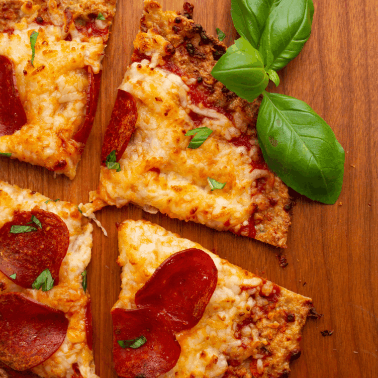 Golden chicken crust pizza topped with melted cheese, sauce, and fresh herbs cooked in the air fryer.