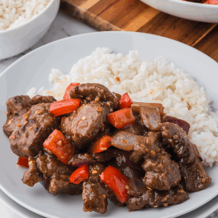 Plate of crispy air fryer Beijing beef with red peppers and tangy sauce.