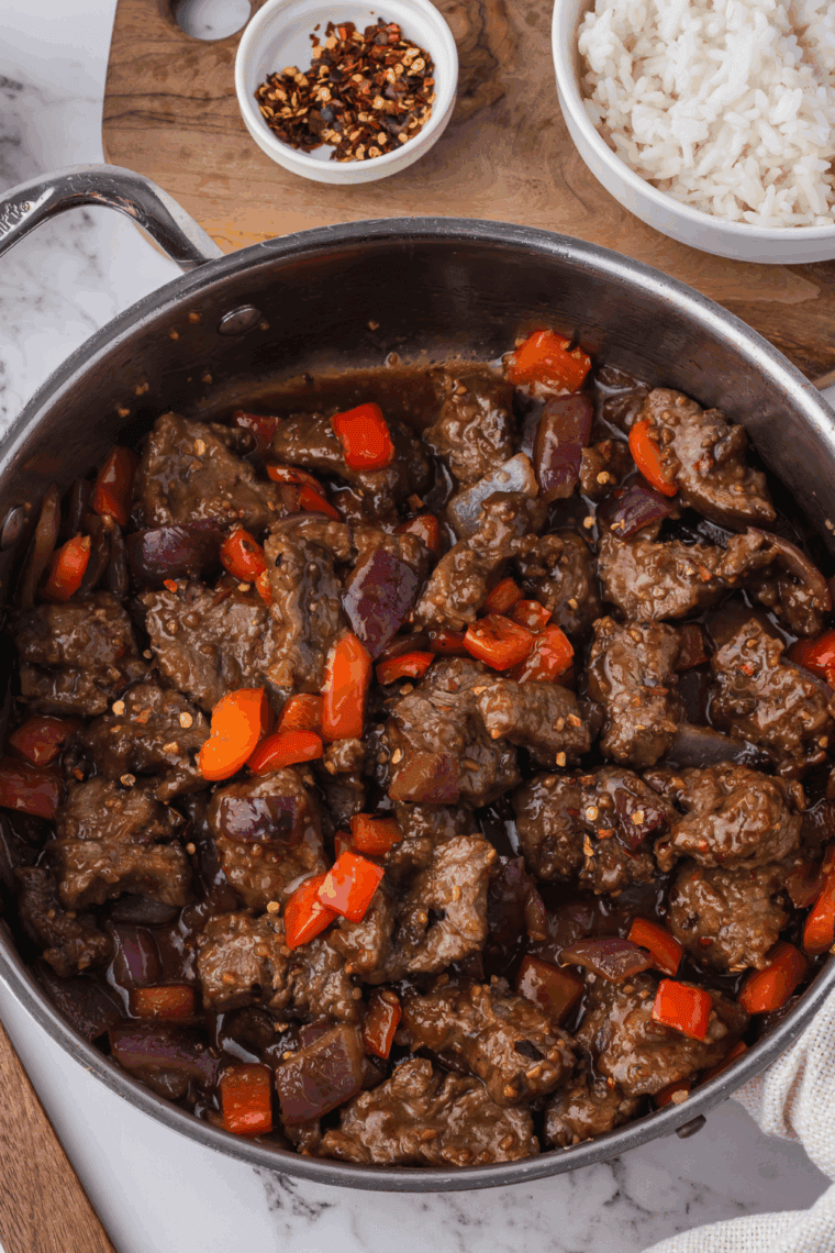 Air fryer Beijing beef with red bell peppers and onions in a glossy sauce.