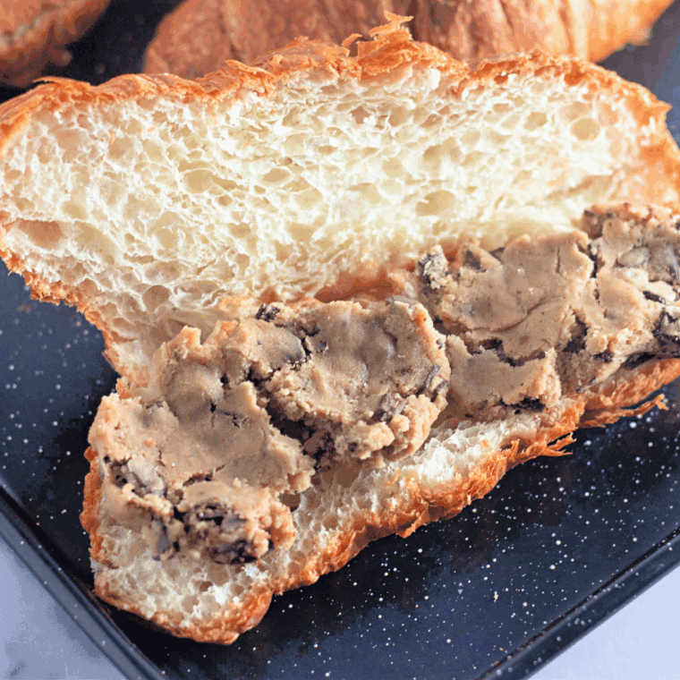 Stuffing croissant with chocolate chip cookie dough and gently pressing it closed.