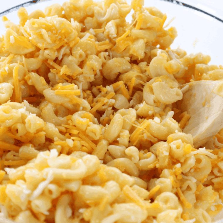 Mixing macaroni and cheese in a large mixing bowl, to make the cheesy filling.