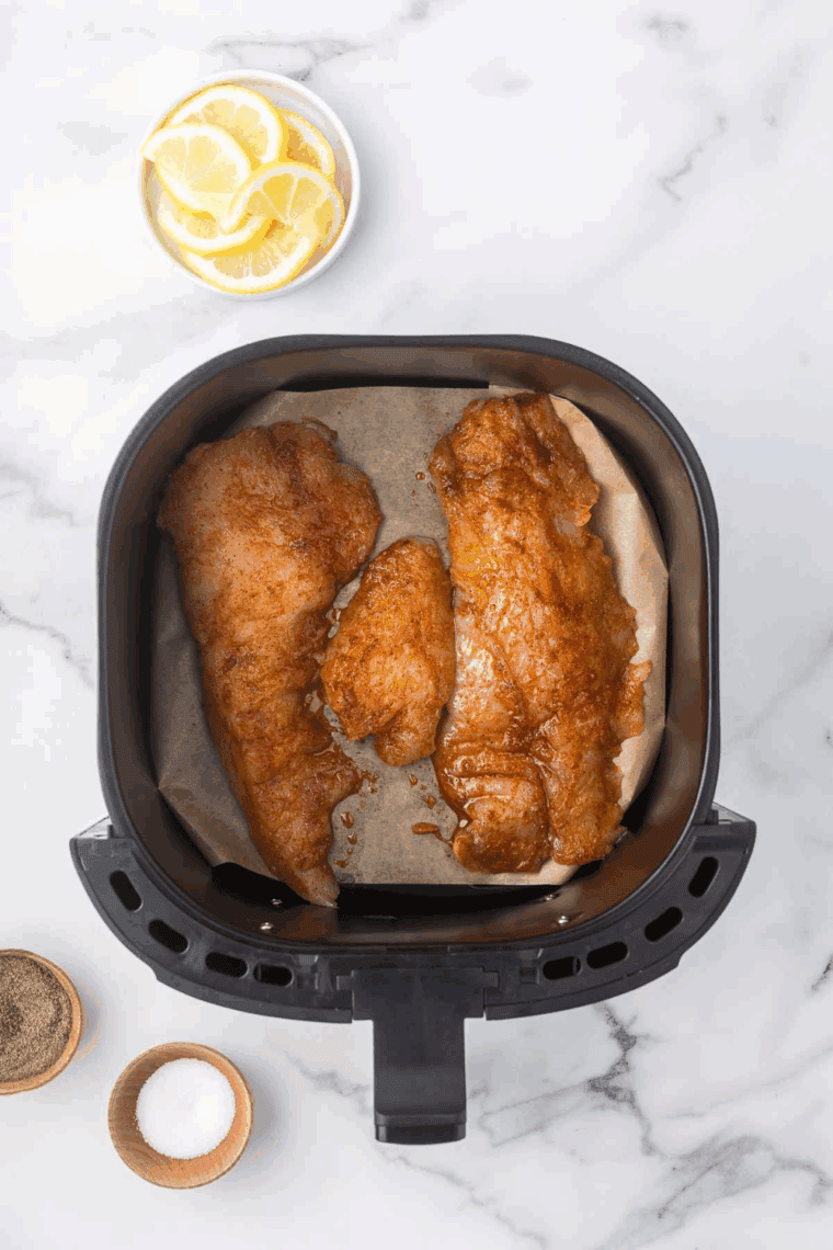 Monkfish fillets arranged in a single layer in the air fryer basket.