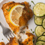 Crispy, golden-brown air fryer monkfish fillets served with lemon wedges and herbs.