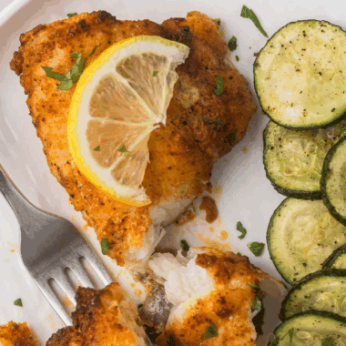 Crispy, golden-brown air fryer monkfish fillets served with lemon wedges and herbs.