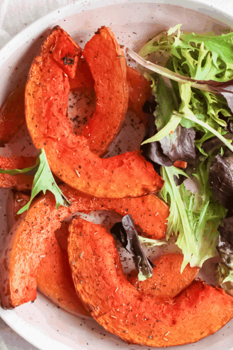 Crispy seasoned pumpkin wedges cooked in an air fryer, served on a plate.