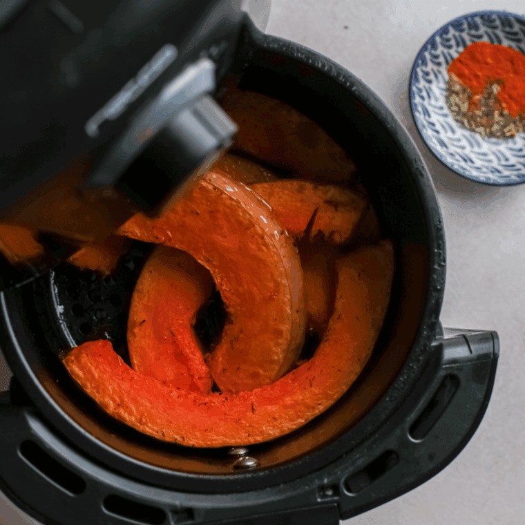 Roasted pumpkin wedges in the air fryer basket.
