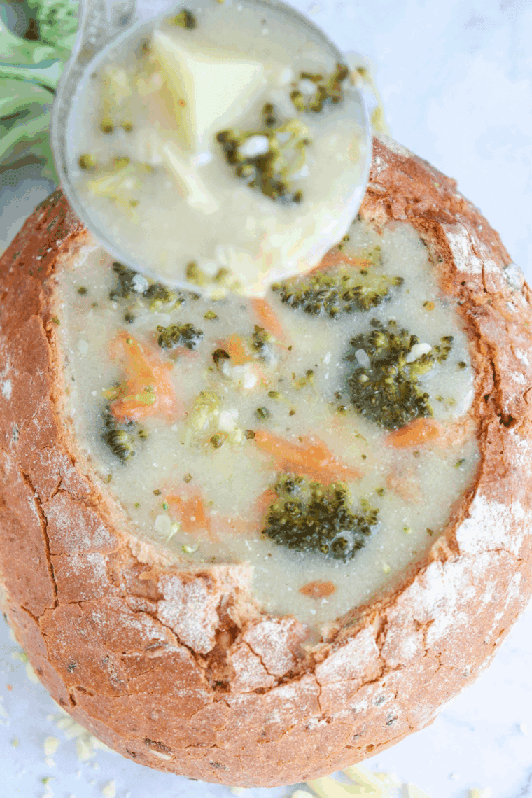 Bowl of Applebee’s broccoli cheese soup garnished with cheddar and served with bread