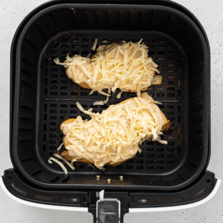 Brushing cooked chicken with sauce, topping with cheese, and melting in air fryer.