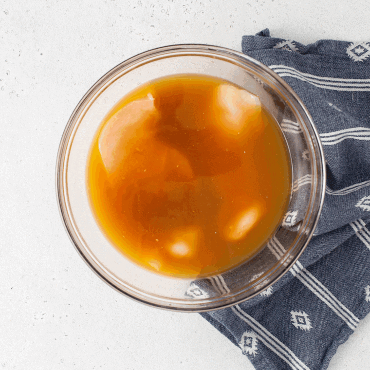Mixing marinade ingredients and adding chicken breasts to marinate in bowl.