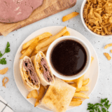 Homemade Arby’s Classic French Dip sandwich with melted cheese and au jus for dipping