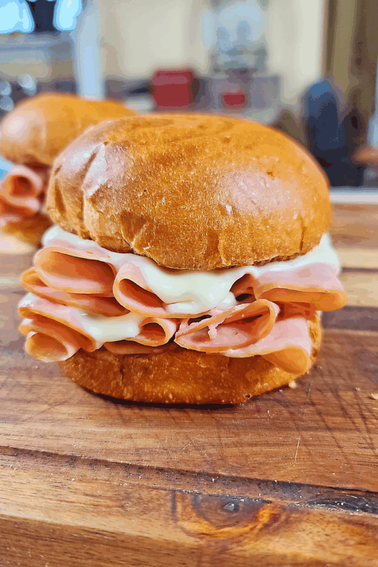 Close-up of a toasted Arby’s-style ham and cheese melt sandwich with melted cheese and ham inside.