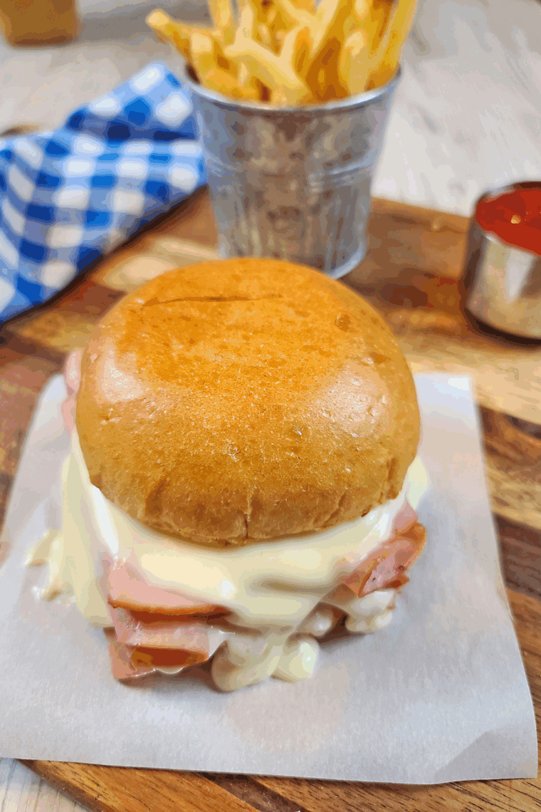 Close-up of a homemade Arby’s ham and cheese melt sandwich with melted cheese and sliced ham on a toasted bun.