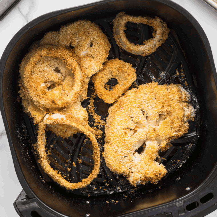 Crispy air fryer Arby’s-style onion rings stacked on a plate.

