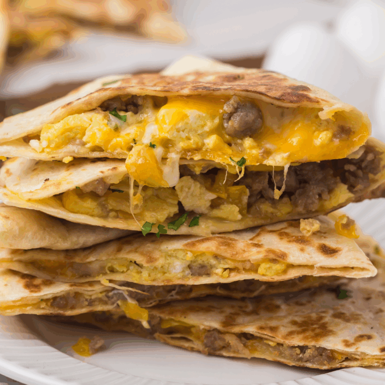 Golden breakfast quesadilla cooking on Blackstone griddle, filled with eggs, sausage, bell peppers, and melted cheese.