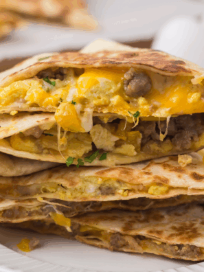 Crispy Blackstone breakfast quesadillas filled with eggs, cheese, and sausage, sliced and served on a griddle.