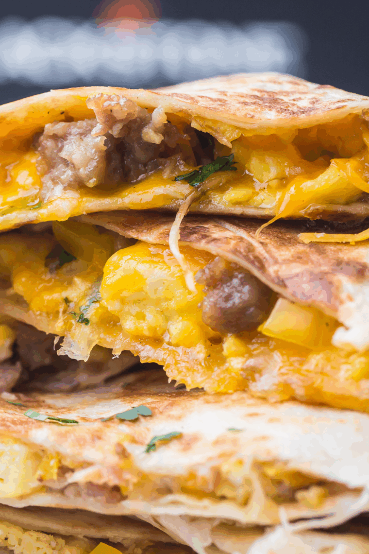 Golden brown Blackstone breakfast quesadilla filled with eggs, sausage, bell peppers, and melted cheese cooking on a griddle.