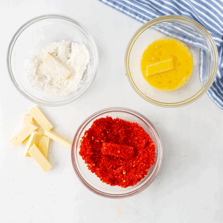 Breading the mozzarella sticks in each bowl to create a crispy coating.