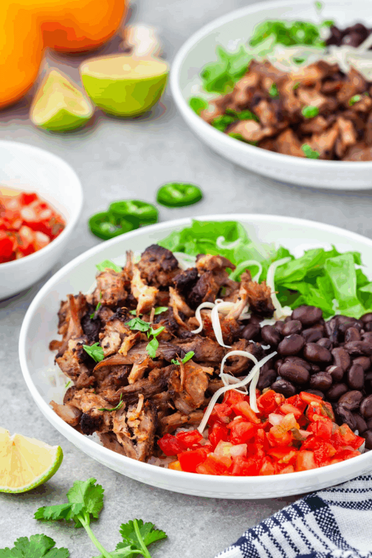 Discover a simple, but flavorful Carnitas Burrito Bowl, inspired by Chipotle, it's amazing, served with black beans, diced tomatoes and lettuce. A perfect meal.
