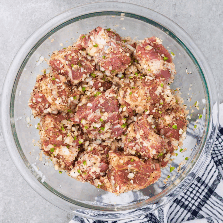 Carnitas meat marinating in large mixing bowl.