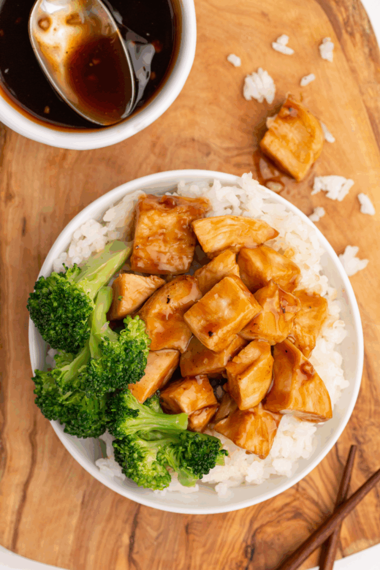 Sliced chipotle honey chicken on a plate with lime wedges and fresh herbs, ready to serve.