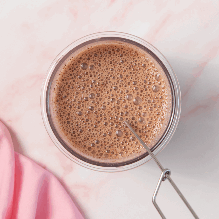 Whisking chocolate milk, protein powder, and pudding mix in a Ninja Creami pint container before freezing for 24 hours.