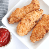 Golden crispy homemade chicken tenders served with dipping sauce.